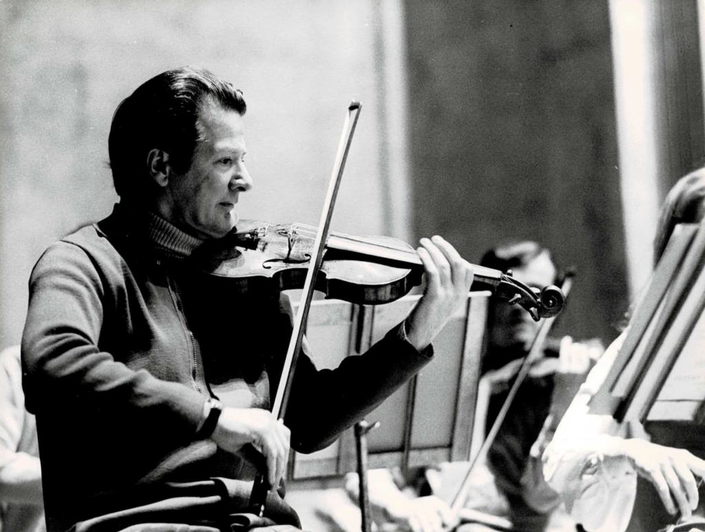 A black-and-white close-up of Neville Marriner in the late 1960s, directing from the front desk of violins – a position he would not fully relinquish until the mid-1970s.